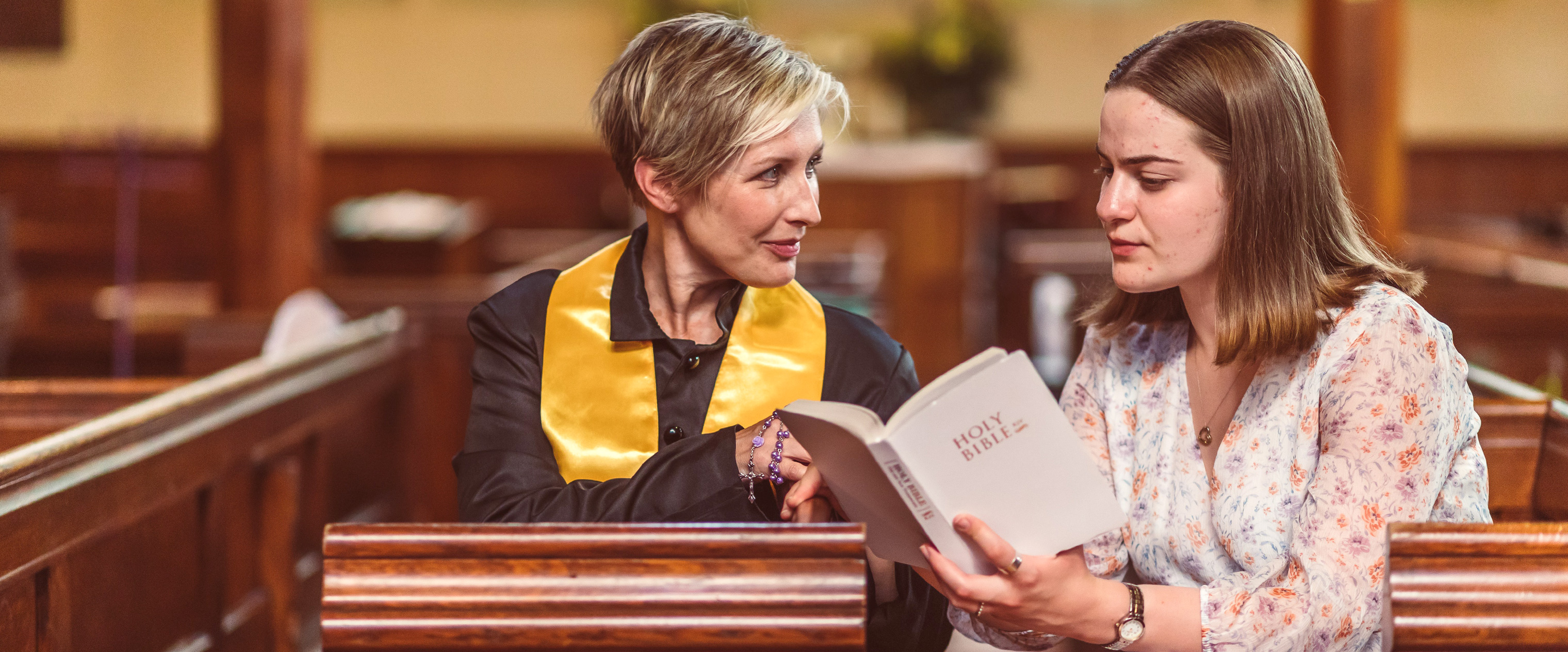 Woman priest speaking with a member of the congregation in church