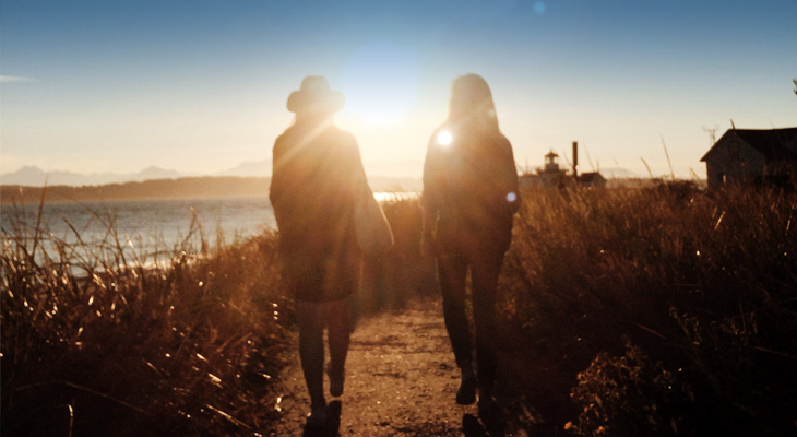 Two people walking along a path toward sunrise image