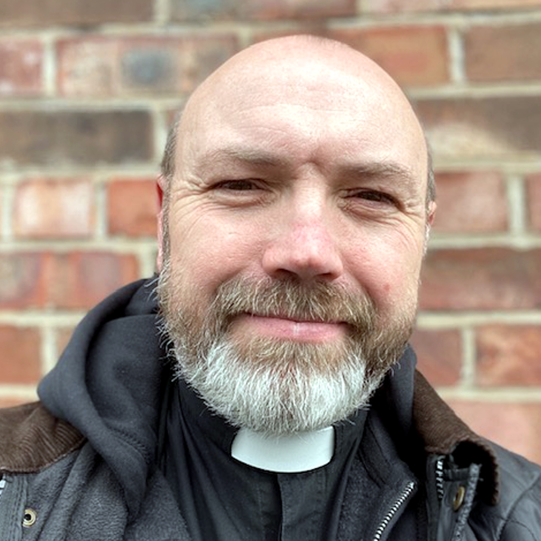 Head and Shoulder photograph of our New Director of Ordinands Harry Wood, stood in front of a brick wall